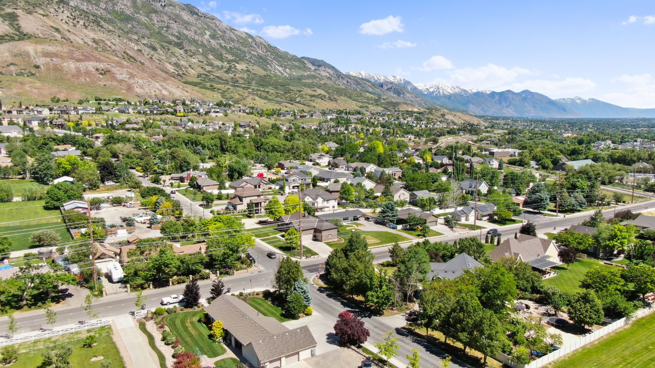Utah neighborhood beneath the Wasatch Mountains with mature trees, established homes, and mountain views.