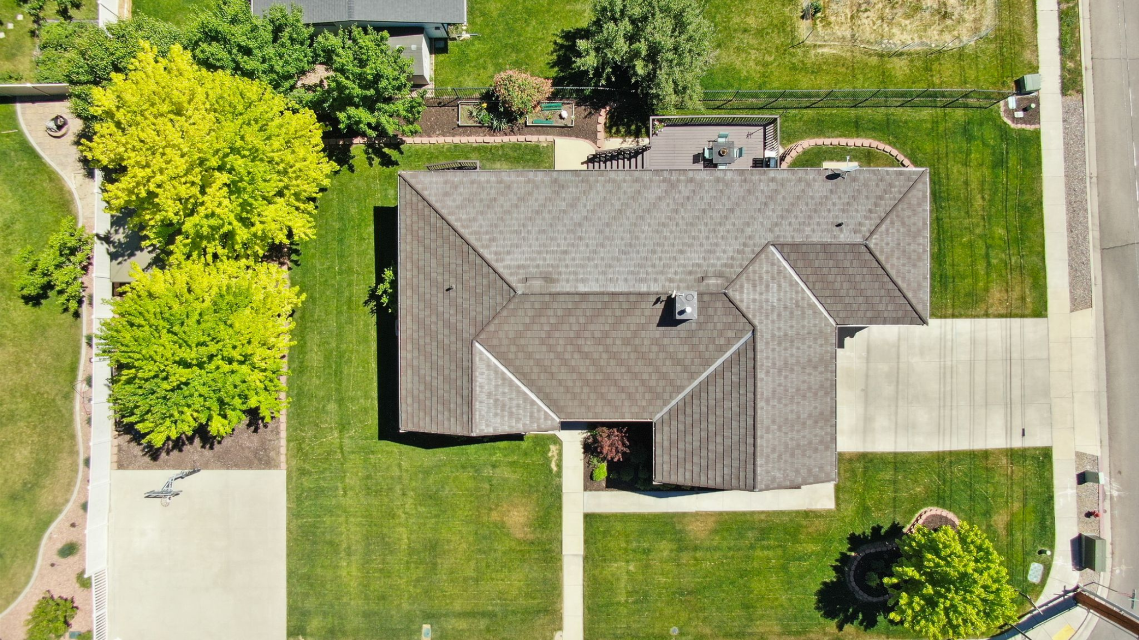Aerial view of an established Utah home on a spacious landscaped lot with mature trees and outdoor living areas.