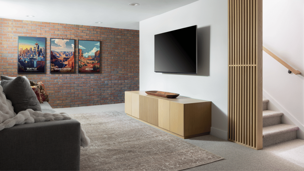 Finished basement family room with an exposed brick accent wall, white oak divider, and mounted TV.