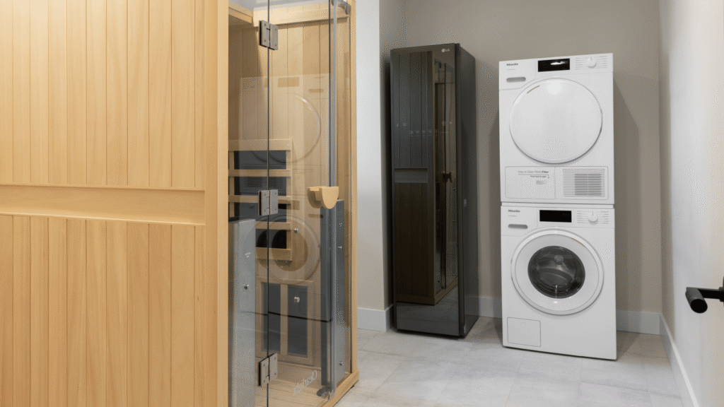 Custom home sauna beside a stacked washer, dryer, and steam cabinet in a remodeled master closet.